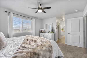 Carpeted bedroom with ensuite bath and ceiling fan