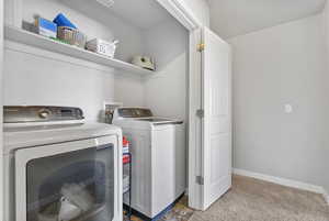 Washroom featuring light colored carpet and washing machine and clothes dryer