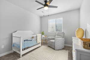 Carpeted bedroom with ceiling fan and a crib