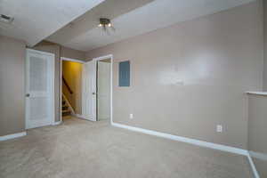 Unfurnished bedroom featuring a textured ceiling, electric panel, and light colored carpet