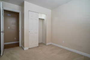 Unfurnished bedroom with light carpet and a closet