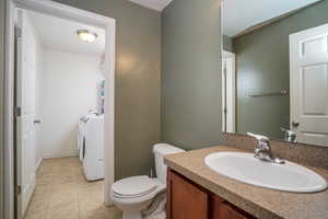 Bathroom with tile patterned flooring, vanity, toilet, and washing machine and clothes dryer