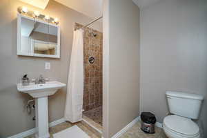 Bathroom featuring tile patterned flooring, toilet, curtained shower, and sink