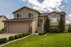 Split level home featuring a garage and a front lawn