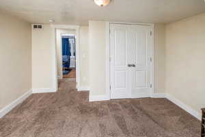 Unfurnished bedroom with a closet, carpet floors, and a textured ceiling