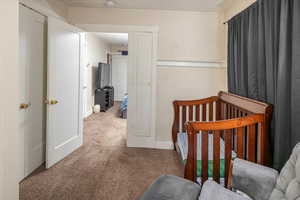 Bedroom with carpet flooring, a crib, and a textured ceiling