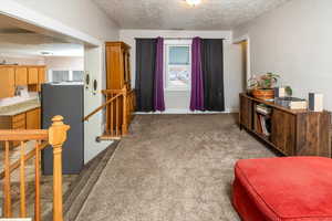 Living area with dark colored carpet and a textured ceiling