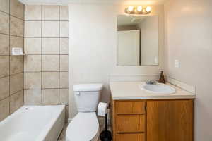 Bathroom featuring a washtub, vanity, and toilet