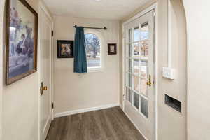 Doorway to outside featuring dark wood-type flooring and a textured ceiling