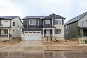 View of front of home featuring stone siding, board and batten siding, concrete driveway, and an attached garage