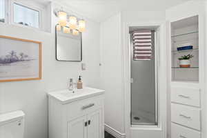 Bathroom with vanity, toilet, and an enclosed shower