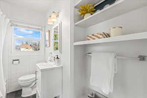 Full bathroom with vanity, toilet, tile walls, and shower / tub combo with curtain