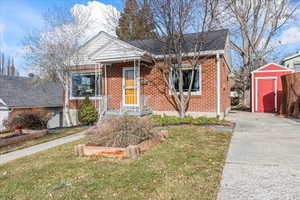 Bungalow-style home with a front lawn and a storage unit