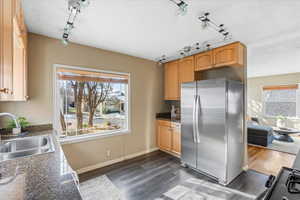 Kitchen with rail lighting, stainless steel refrigerator, dark wood-type flooring, and sink