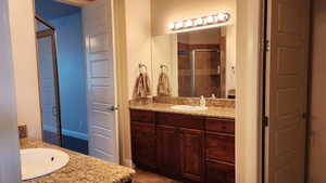 Bathroom with tile patterned flooring, vanity, and a shower with door