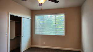 Unfurnished bedroom featuring multiple windows, ceiling fan, a closet, and carpet floors