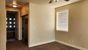 Spare room featuring ceiling fan and dark carpet