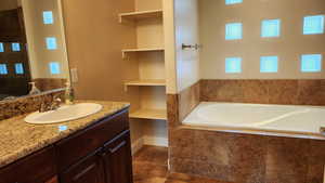 Bathroom featuring vanity and tiled bath