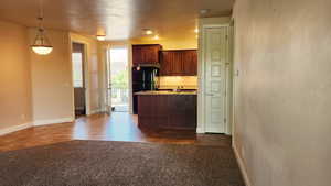 Kitchen featuring decorative light fixtures, black fridge, dark tile patterned floors, and sink