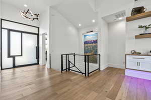 Entrance foyer with a chandelier, light hardwood / wood-style flooring, and high vaulted ceiling