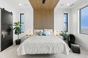 Bedroom with a barn door, carpet floors, and multiple windows