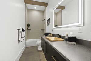 Full bathroom with tile patterned flooring, vanity, toilet, and tiled shower / bath combo