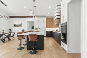 Kitchen with white cabinetry, a kitchen island with sink, a breakfast bar, and pendant lighting