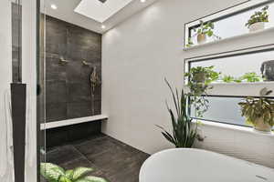 Bathroom with a skylight, tile walls, and a bathing tub