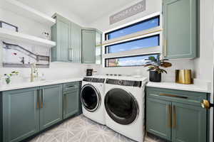 Laundry room with cabinets, washer and clothes dryer, and sink