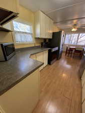 Kitchen featuring ceiling fan, light wood-type flooring, a wealth of natural light, white cabinetry, and stainless steel appliances