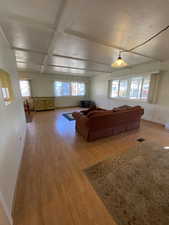 Unfurnished living room with beamed ceiling, light hardwood / wood-style floors, and coffered ceiling