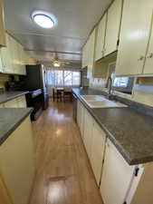 Kitchen featuring ceiling fan, sink, black electric range, stainless steel dishwasher, and light wood-type flooring