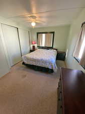 Bedroom with ceiling fan, light carpet, and a closet