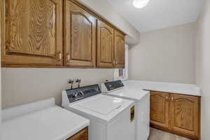 Laundry area with cabinets, independent washer and dryer, and light hardwood / wood-style flooring