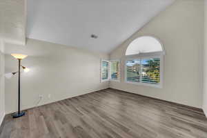 Spare room with light hardwood / wood-style flooring and vaulted ceiling