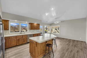 Kitchen with stainless steel dishwasher, sink, lofted ceiling, a center island, and a breakfast bar area