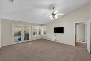 Unfurnished living room with ceiling fan, lofted ceiling, carpet floors, and french doors