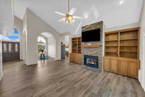 Unfurnished living room featuring ceiling fan, a fireplace, high vaulted ceiling, and light hardwood / wood-style floors