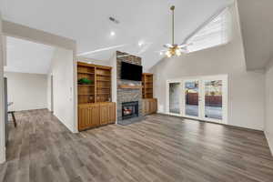 Unfurnished living room with ceiling fan, a fireplace, high vaulted ceiling, and hardwood / wood-style flooring