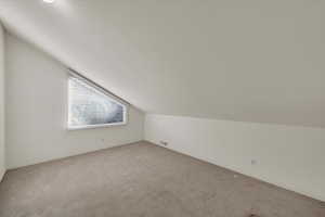 Bonus room featuring light colored carpet and lofted ceiling