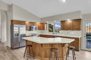 Kitchen featuring a breakfast bar, backsplash, stainless steel appliances, and tile counters