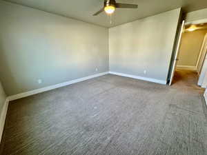 Empty room featuring ceiling fan and carpet