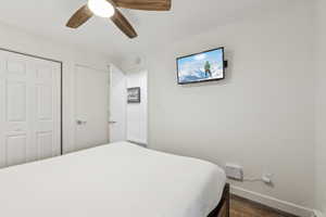 Bedroom featuring ceiling fan, dark wood-type flooring, and a closet