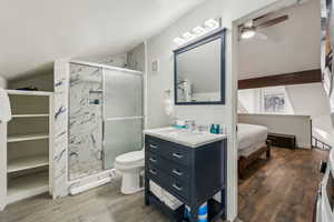 Bathroom featuring ceiling fan, toilet, a shower with shower door, and wood-type flooring