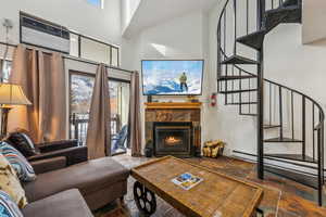 Living room with a fireplace, a towering ceiling, an AC wall unit, and a wealth of natural light