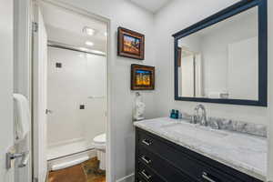 Bathroom featuring vanity, toilet, and a shower with door