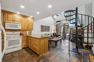 Kitchen with decorative backsplash, white appliances, and kitchen peninsula