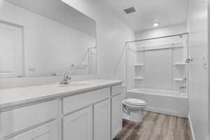 Full bathroom featuring toilet, vanity, shower / bath combination, and wood-type flooring