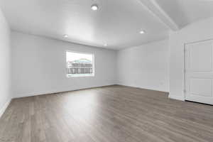 Empty room with beam ceiling, light hardwood / wood-style floors, and a textured ceiling