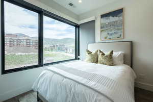 Bedroom with multiple windows, a mountain view, and hardwood / wood-style floors